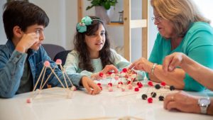 Grandmother playing educational games with grandchildren indoors, fostering creativity and learning.